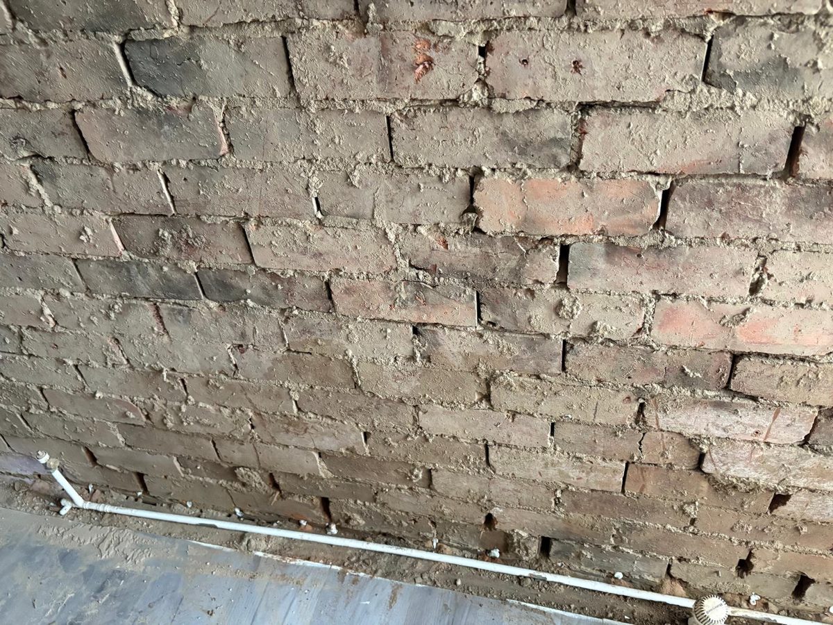 Exposed brickwork with damp proof course injection holes plugged along the mortar bed