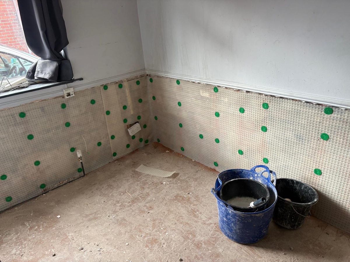 Damp proof membrane carried around a room corner and cut around the sockets, buckets on the bare floor